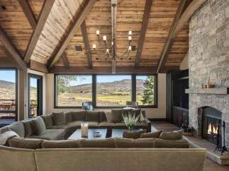 Experience luxurious mountain living in this stunning great room, featuring a massive stone fireplace and a vaulted wood-beamed ceiling.