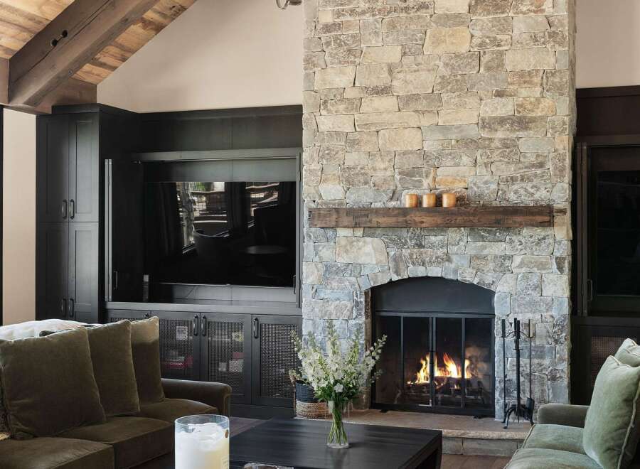 Experience rustic elegance in this living room, featuring a grand stone fireplace with a reclaimed wood mantel, perfect for cozy evenings.