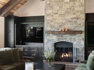 Experience rustic elegance in this living room, featuring a grand stone fireplace with a reclaimed wood mantel, perfect for cozy evenings.