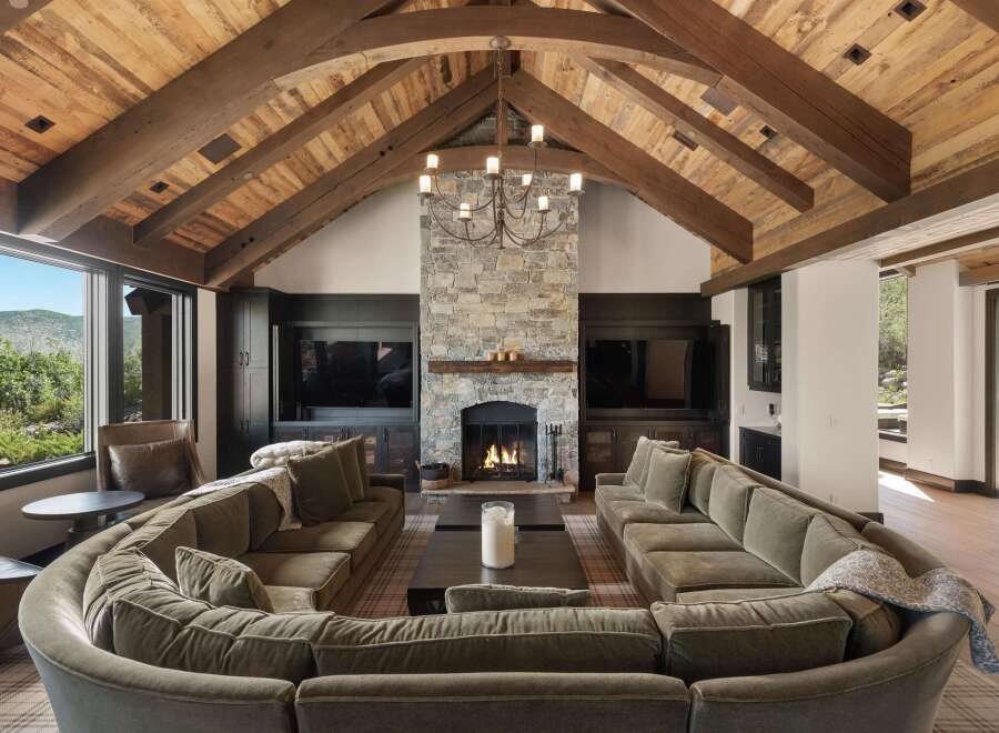 Experience luxury mountain living in this stunning great room, featuring a dramatic vaulted wood-beamed ceiling and a grand stone fireplace.