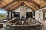 Experience luxury mountain living in this stunning great room, featuring a dramatic vaulted wood-beamed ceiling and a grand stone fireplace.