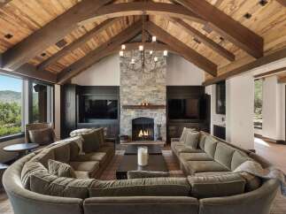 Experience luxury mountain living in this stunning great room, featuring a dramatic vaulted wood-beamed ceiling and a grand stone fireplace.