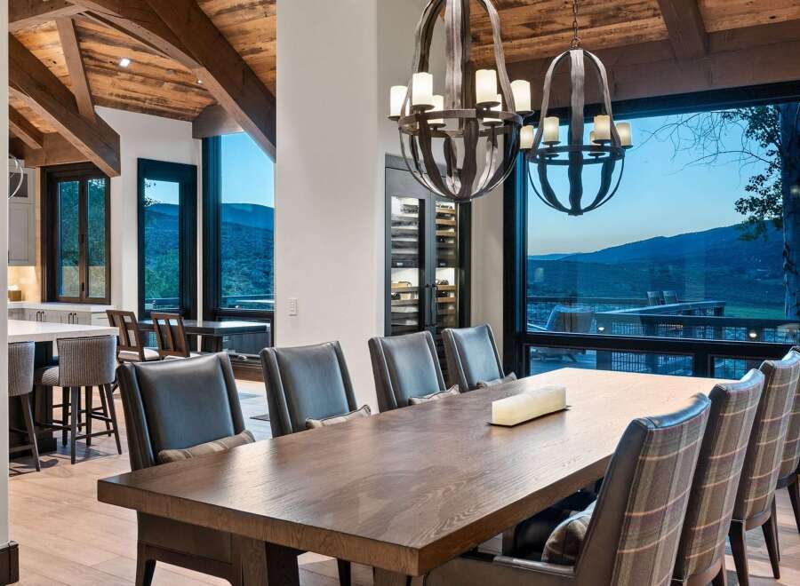 Experience luxurious mountain living in this stunning dining room, featuring a grand wooden table and plush seating perfect for hosting.