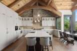 Experience luxury mountain living in this stunning gourmet kitchen, featuring custom white cabinetry, a large island with a waterfall countertop, and a professional-grade range.