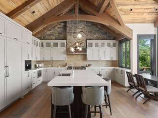 Experience luxury mountain living in this stunning gourmet kitchen, featuring custom white cabinetry, a large island with a waterfall countertop, and a professional-grade range.