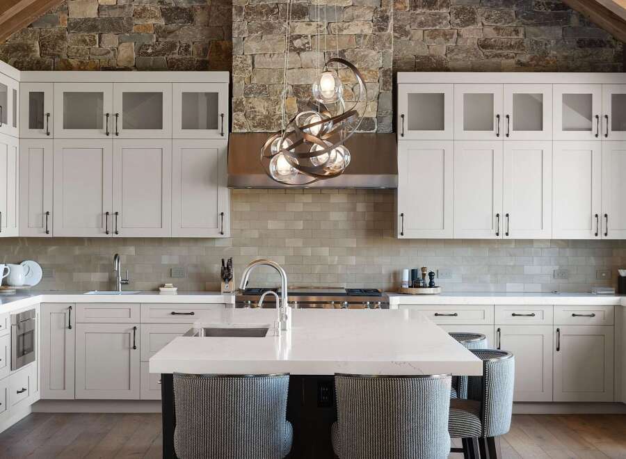 Experience luxury in this stunning kitchen featuring sleek white cabinetry and a striking stone accent wall.