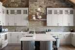 Experience luxury in this stunning kitchen featuring sleek white cabinetry and a striking stone accent wall.