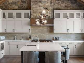 Experience luxury in this stunning kitchen featuring sleek white cabinetry and a striking stone accent wall.