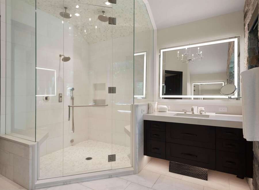 Experience luxury in this stunning bathroom featuring a spacious glass-enclosed shower with multiple showerheads and a built-in bench.