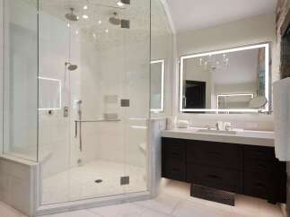 Experience luxury in this stunning bathroom featuring a spacious glass-enclosed shower with multiple showerheads and a built-in bench.