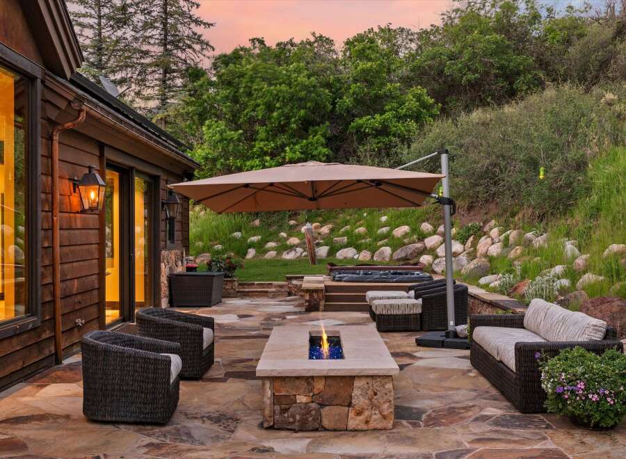 Experience outdoor living at its finest with this luxurious patio featuring a modern fire pit and a relaxing hot tub.