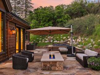 Experience outdoor living at its finest with this luxurious patio featuring a modern fire pit and a relaxing hot tub.