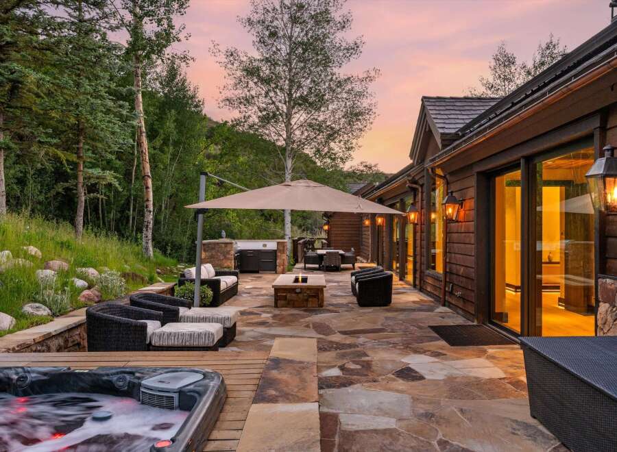 Experience luxurious outdoor living with this stunning patio featuring a bubbling hot tub, a built-in grill, and a cozy fire pit.
