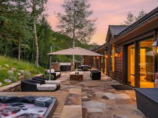 Experience luxurious outdoor living with this stunning patio featuring a bubbling hot tub, a built-in grill, and a cozy fire pit.