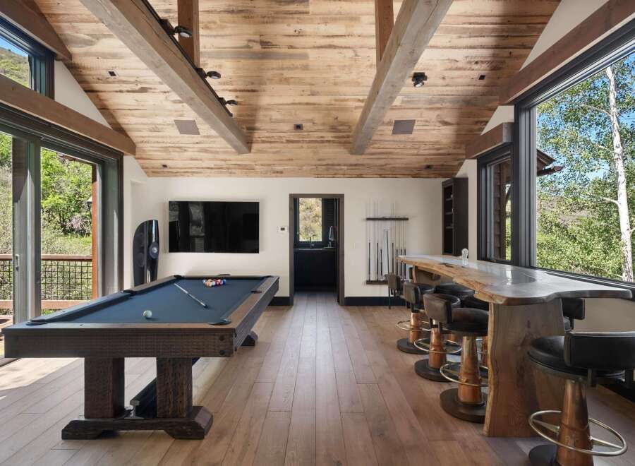 Experience ultimate relaxation and entertainment in this stunning game room, featuring a professional pool table and a live-edge bar with plush seating.
