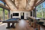 Experience ultimate relaxation and entertainment in this stunning game room, featuring a professional pool table and a live-edge bar with plush seating.