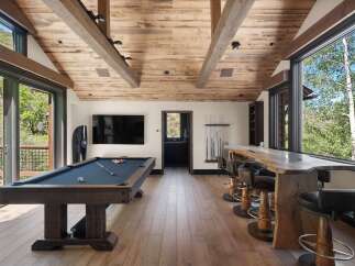 Experience ultimate relaxation and entertainment in this stunning game room, featuring a professional pool table and a live-edge bar with plush seating.