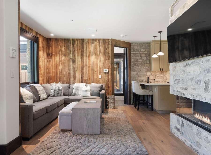 Experience rustic charm and modern comfort in this inviting living space, featuring a cozy sectional sofa complemented by a plush rug and a stylish coffee table.