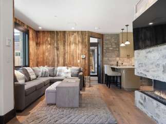 Experience rustic charm and modern comfort in this inviting living space, featuring a cozy sectional sofa complemented by a plush rug and a stylish coffee table.