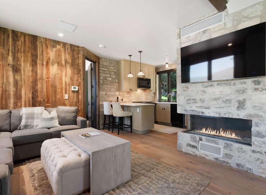 Experience modern mountain living in this stunning open-concept living space, featuring a cozy sectional sofa and a large, modern fireplace with a mounted TV.