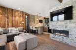 Experience modern mountain living in this stunning open-concept living space, featuring a cozy sectional sofa and a large, modern fireplace with a mounted TV.