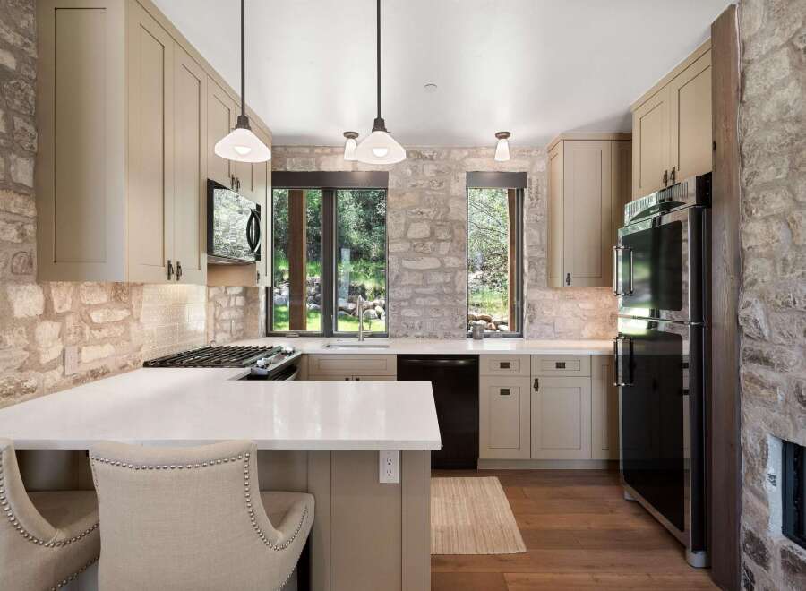 Experience rustic charm in this beautifully appointed kitchen, featuring a striking stone accent wall and warm, neutral cabinetry.
