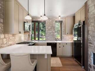 Experience rustic charm in this beautifully appointed kitchen, featuring a striking stone accent wall and warm, neutral cabinetry.