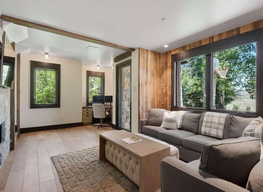 This inviting living space features a cozy stone fireplace and a dedicated workspace with dual monitors, perfect for remote work.