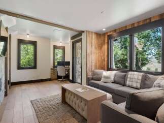 This inviting living space features a cozy stone fireplace and a dedicated workspace with dual monitors, perfect for remote work.
