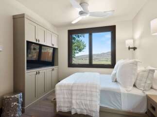 Experience serene mountain living in this charming bedroom, featuring a built-in entertainment center and a large window with breathtaking views.