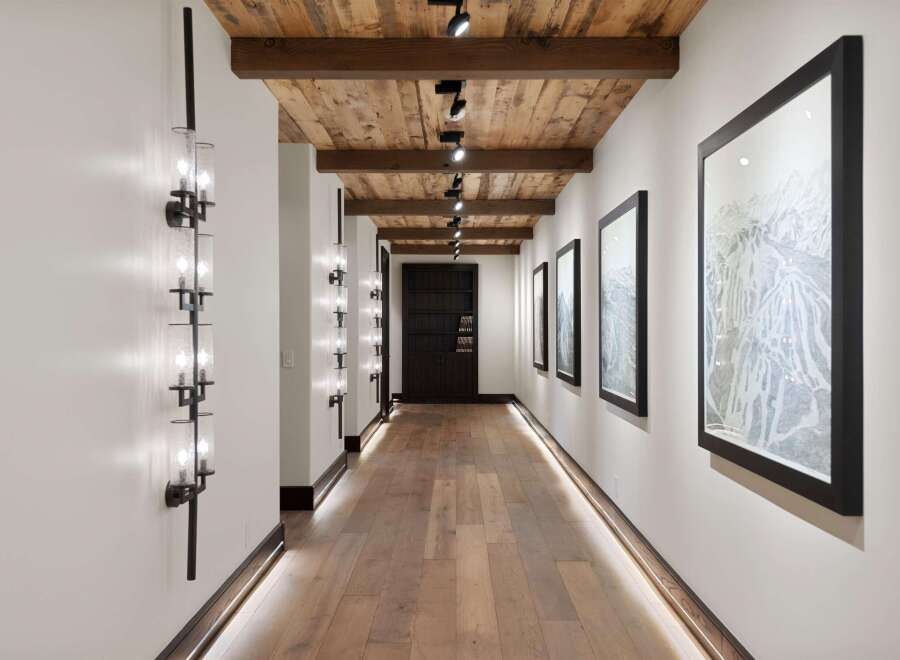 Experience luxury mountain living in this stunning hallway featuring a rustic wood-planked ceiling with exposed beams and modern track lighting.