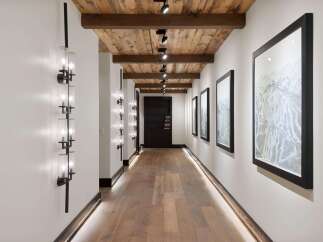 Experience luxury mountain living in this stunning hallway featuring a rustic wood-planked ceiling with exposed beams and modern track lighting.