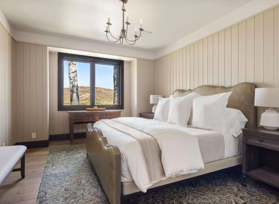 Experience serene mountain living in this beautifully appointed bedroom, featuring a plush king-size bed and a charming chandelier.