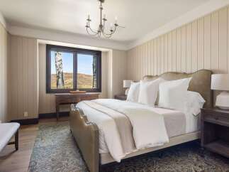 Experience serene mountain living in this beautifully appointed bedroom, featuring a plush king-size bed and a charming chandelier.