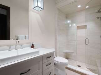 Experience modern luxury in this stunning bathroom featuring a sleek vanity with a vessel sink and a spacious glass-enclosed shower.