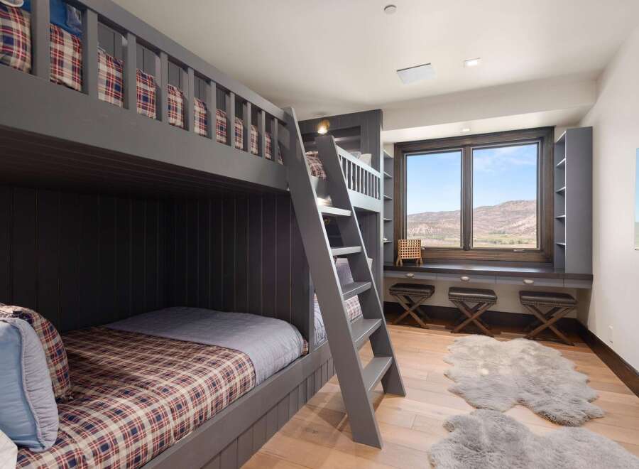 This charming bedroom features a custom-built gray bunk bed with plaid bedding, perfect for accommodating guests or family.