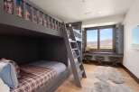 This charming bedroom features a custom-built gray bunk bed with plaid bedding, perfect for accommodating guests or family.