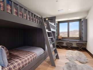 This charming bedroom features a custom-built gray bunk bed with plaid bedding, perfect for accommodating guests or family.