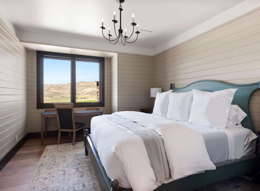 Experience serene mountain living in this charming bedroom, featuring a comfortable king-size bed adorned with crisp white linens and a soft grey throw.