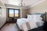 Experience serene mountain living in this charming bedroom, featuring a comfortable king-size bed adorned with crisp white linens and a soft grey throw.