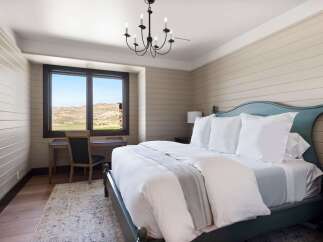 Experience serene mountain living in this charming bedroom, featuring a comfortable king-size bed adorned with crisp white linens and a soft grey throw.