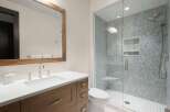 Experience modern luxury in this stunning bathroom, featuring a sleek vanity with a white countertop and a spacious glass-enclosed shower adorned with intricate mosaic tile.