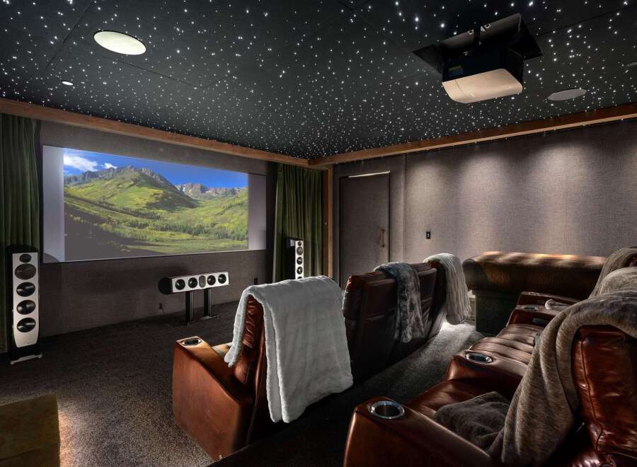 Experience cinematic luxury in this state-of-the-art home theater, featuring plush leather recliners with built-in cup holders and cozy throws.