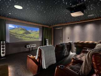 Experience cinematic luxury in this state-of-the-art home theater, featuring plush leather recliners with built-in cup holders and cozy throws.