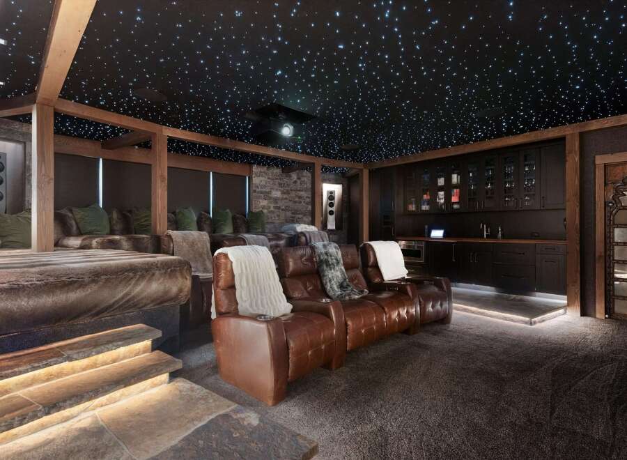 Experience ultimate relaxation in this luxurious home theater, complete with plush leather recliners and a stunning starry night ceiling.