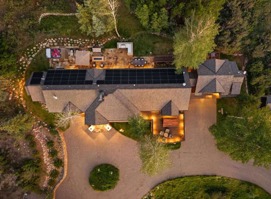 Experience luxury living with this stunning aerial view of a modern home featuring a spacious deck, an inviting hot tub, and a large patio perfect for outdoor entertaining.
