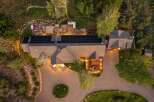 Experience luxury living with this stunning aerial view of a modern home featuring a spacious deck, an inviting hot tub, and a large patio perfect for outdoor entertaining.