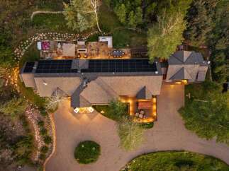 Experience luxury living with this stunning aerial view of a modern home featuring a spacious deck, an inviting hot tub, and a large patio perfect for outdoor entertaining.