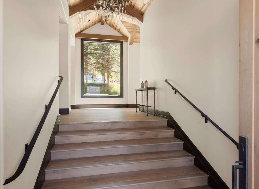 Ascend to luxury in this stunning mountain home, featuring a grand staircase with rich wood treads and a sleek black handrail.