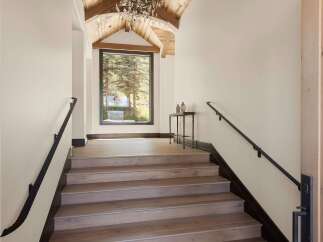 Ascend to luxury in this stunning mountain home, featuring a grand staircase with rich wood treads and a sleek black handrail.